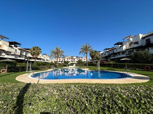 uma piscina num parque com palmeiras e edifícios em Ático junto al Mar,Acceso directo a la playa,Jardines de Nuevo Vera,WIFI em Vera