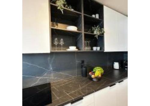 a kitchen with white cabinets and a black counter top at On The Sea Suite&Spa in Methana