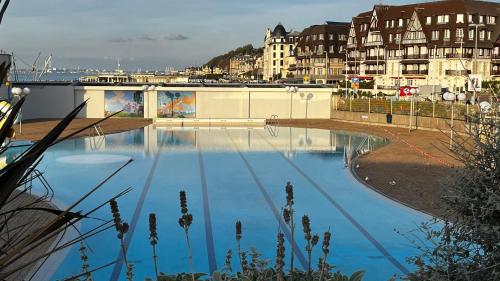 un grand bassin d'eau bleue avec des bâtiments en arrière-plan dans l'établissement Petite Bulle, à Trouville-sur-Mer