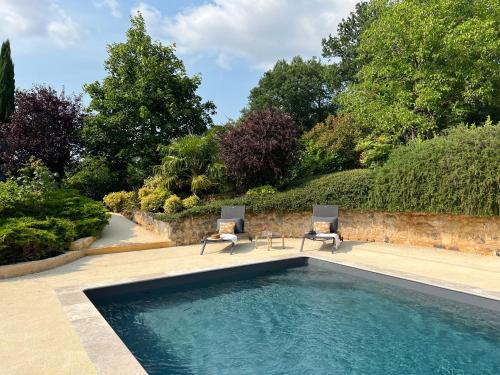 - une piscine avec 2 chaises assises à côté dans l'établissement Le Clos Saint James 5 étoiles, à Domme