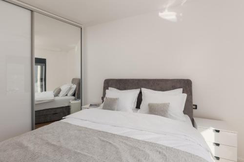 a bedroom with a white bed with a large mirror at Berge Apartments in Kotor