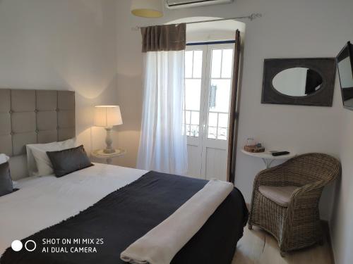 1 dormitorio con 1 cama, 1 silla y 1 ventana en Casa da Tia Amalia, en Mértola