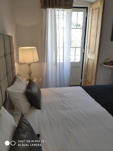 a bedroom with a bed with a window and a lamp at Casa da Tia Amalia in Mértola