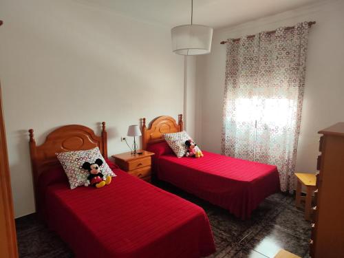 Bernal I, II y III في Los Sauces: غرفة نوم بسريرين عليهما شرشف احمر ودببة