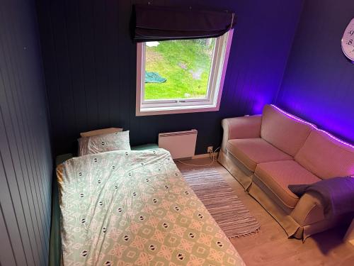 a bedroom with a bed and a couch and a window at Sagavang in Trondheim