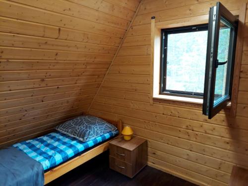 1 cama en una cabaña de madera con ventana en Chatka Góralska w Borkowie, en Borkowo