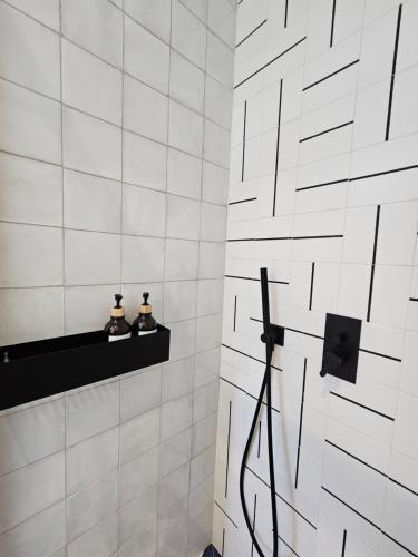 a white tiled bathroom with a black shelf at The Singular - Downtown Studio in Faro