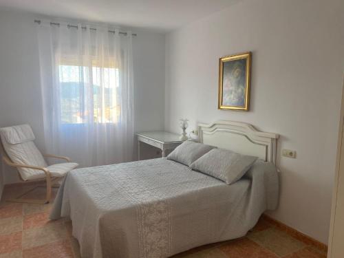 a bedroom with a bed and a chair and a window at Apartamento El Mirador de Sierra Mágina Noalejo entre Granada y Jaén in Noalejo