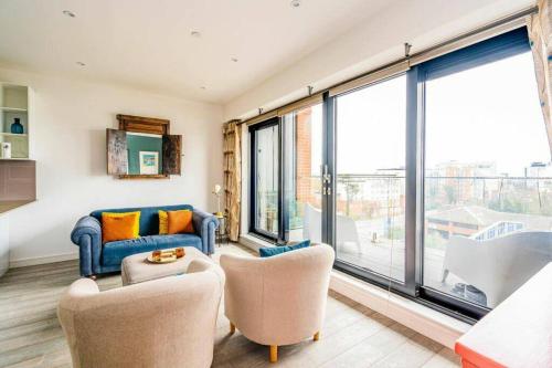 ein Wohnzimmer mit einem Sofa, Stühlen und Fenstern in der Unterkunft easyStay Bath Road Slough in Slough