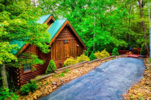 a log cabin in the woods next to a driveway at CABIN in a GATED RESORT with SEASONAL RESORT POOL in Pigeon Forge