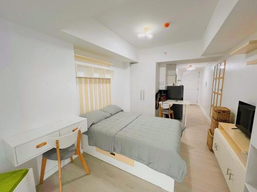 een slaapkamer met een bed, een bureau en een televisie bij Azure North Residences by ACC in Lagundi