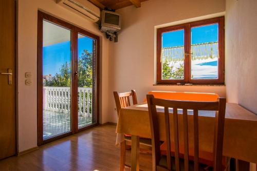 a dining room with a table and two windows at Apartments Žile in Starigrad