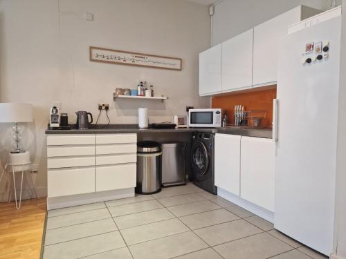 a kitchen with white cabinets and a washer and dryer at Lovely London on a budget! in London
