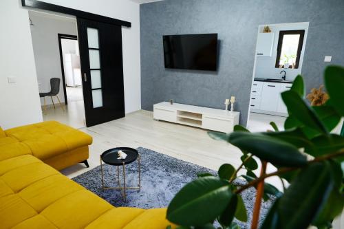 a living room with a yellow couch and a tv at RDT Guest House-Rai din Transilvania in Moieciu de Jos