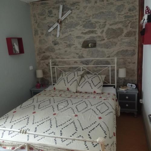 - une chambre avec un lit blanc et un mur en pierre dans l'établissement LA BIGOURDANE, à Cauterets