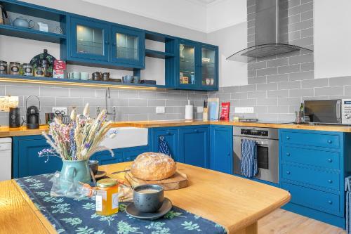 a kitchen with blue cabinets and a table with a loaf of bread at Beeswing, a Victorian Gem in Biggar in Biggar