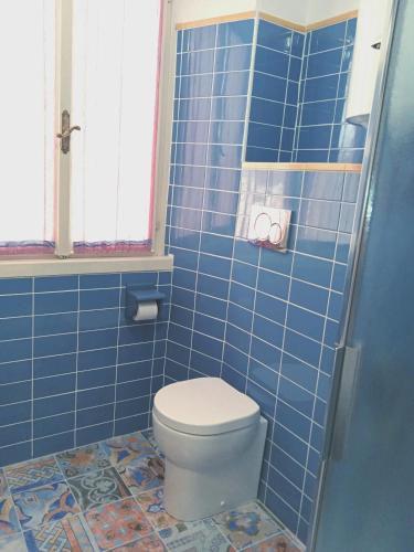 a blue tiled bathroom with a toilet and a window at La casa di Uccia in Trieste