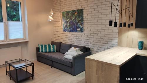 sala de estar con sofá y pared de ladrillo en Be my Guest- Fontany Luxury Apartment Metro Wi-Fi free parking zone, en Varsovia