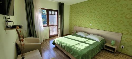 a bedroom with a bed with a green comforter and a window at Complex Turistic Perla Trascaului in Rimetea