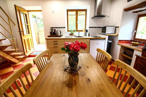 une cuisine avec une table en bois et un vase de fleurs. dans l'établissement LA MAISONNETTE DU POTIER, à Caunes-Minervois