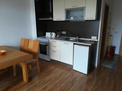 uma cozinha com armários brancos, um lavatório e uma mesa em Large studio apartment , 4* spa resort, The Vineyards. em Aheloy