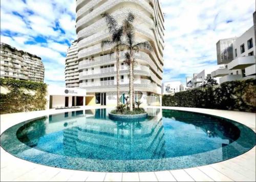 une grande piscine avec un palmier en face d'un bâtiment dans l'établissement Appartement Anfa Park casa finance City CFC, à Casablanca