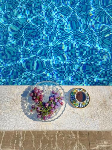 a plate of grapes and a cup of coffee next to a pool at Green House in Virpazar