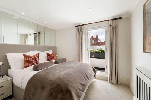 a bedroom with a large bed and a window at South Kensington Luxury Apartment Balcony, Museums & Heathrow 30min in London