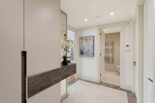 a bathroom with white walls and a hallway with a mirror at South Kensington Luxury Apartment Balcony, Museums & Heathrow 30min in London