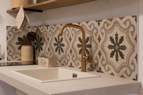 a kitchen sink with a gold faucet on a wall at Rosa Trulli suite in Alberobello