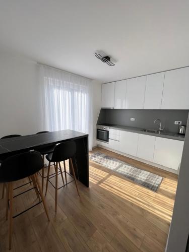 a kitchen with white cabinets and a black table and chairs at Studio Kala in Mostar