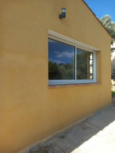 a window on the side of a yellow house at Grand Studio provençal, piscine vue magnifique in Carnoules
