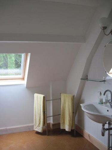 baño blanco con lavabo y ventana en gite de la brasserie, en Saulgé
