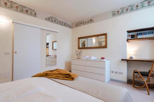 a white bedroom with a bed and a mirror at Iseo Portelle Holiday da Barbara - private parking & bike storage in Iseo