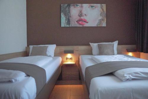 two beds in a room with a painting on the wall at Hotel Frohnhauser Hof in Essen