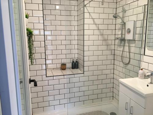 uma casa de banho em azulejos brancos com um chuveiro e um lavatório. em Heron’s View em Arrochar