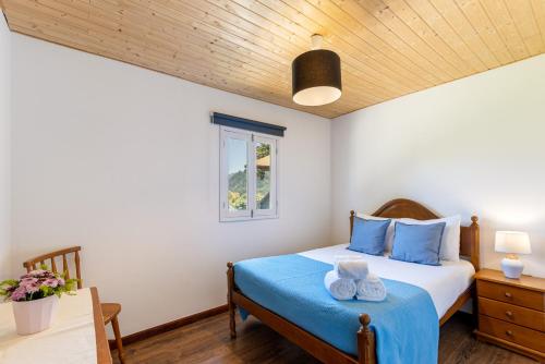 a bedroom with a bed with blue sheets and a window at Chalé da Caniçada By Sé Apartamentos in Rio Caldo