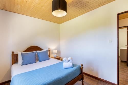 a bedroom with a bed with blue pillows at Chalé da Caniçada By Sé Apartamentos in Rio Caldo