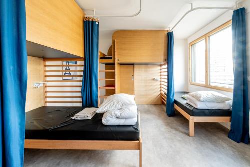 a bedroom with two bunk beds with blue curtains at UCPA SPORT STATION HOSTEL PARIS in Paris