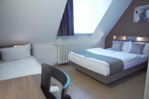 a hotel room with two beds and a table and a chair at Hotel Frohnhauser Hof in Essen