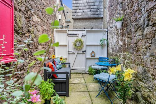 a small courtyard with a table and chairs and flowers at Beeswing, a Victorian Gem in Biggar in Biggar