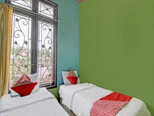 2 Betten in einem Zimmer mit Fenster in der Unterkunft OYO 92872 Swakarya Guest House in Parit