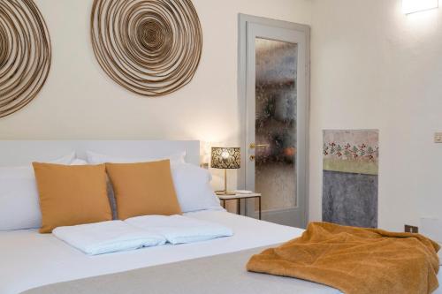 a bedroom with a white bed with white and orange pillows at Iseo Portelle Holiday da Barbara - private parking & bike storage in Iseo