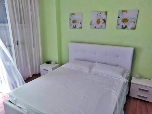 ein Schlafzimmer mit einem weißen Bett mit drei Bildern an der Wand in der Unterkunft Appartamento Igea a 200 m dal mare in Bellaria-Igea Marina