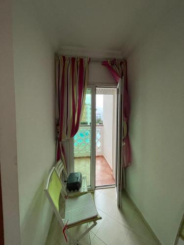 Cette chambre dispose d'une chaise, d'une fenêtre et d'une porte. dans l'établissement Appartement résidence Al Kawtar, à Mohammedia