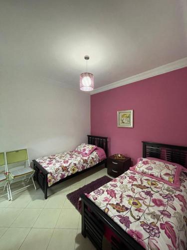 - 2 lits dans une chambre aux murs violets dans l'établissement Appartement résidence Al Kawtar, à Mohammedia