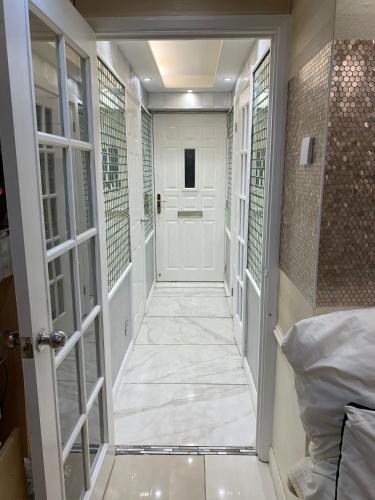 a hallway with a door leading to a room with white tiles at Air Conditioned Modern Double Bed Room with Private Attached Bathroom - FREE Parking - Near London Heathrow Airport & Southall Broadway in Southall