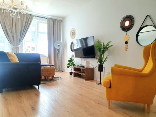 a living room with a blue couch and a yellow chair at Apartament Amber Dwie Sypialnie Stare Miasto in Elblag