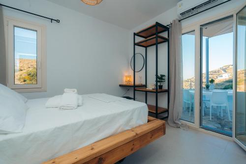 a white bedroom with a bed and large windows at Loukoum House in Kástron