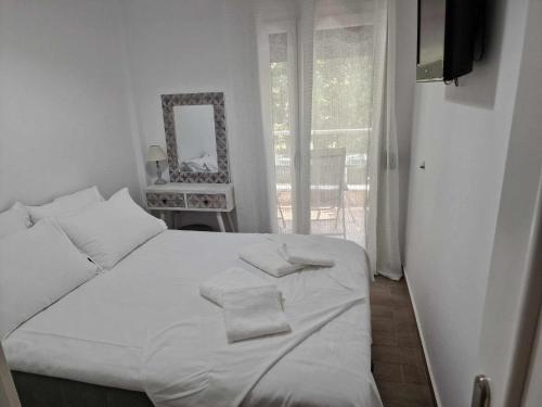 Cama blanca en habitación con ventana en Valentina's Apartment, en Olympiada